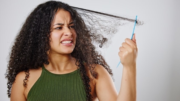 Mulher com cabelo cacheado definido, ela não está usando a melhor escova para cabelo cacheado