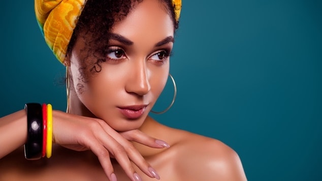 Mulher com cabelos cacheados usando turbante, brincos de argola e pulseiras