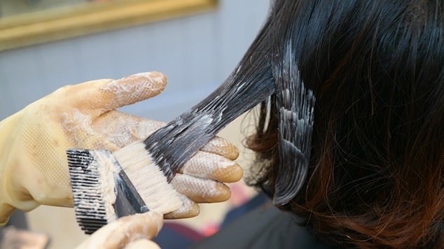 Profissional aplicando a tinta do morena iluminada para cabelo curto