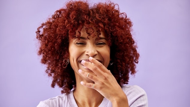 Mulher alegre com o cabelo cacheado de cor vermelho cereja