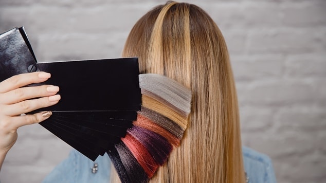 Mulher segurando um catálogo de cores de cabelo para colorimetria, considerando diferentes tons para tingir os fios.