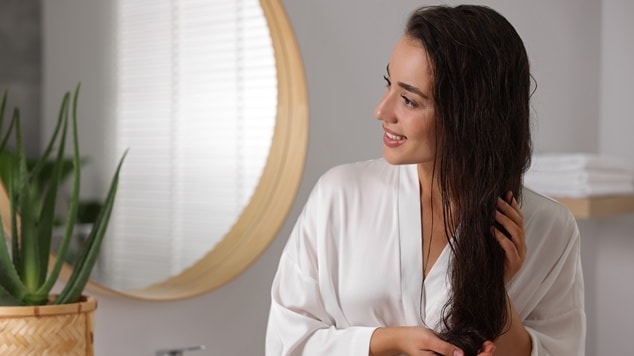 Mulher com cabelos brilhantes e macios após usar acidificante capilar.