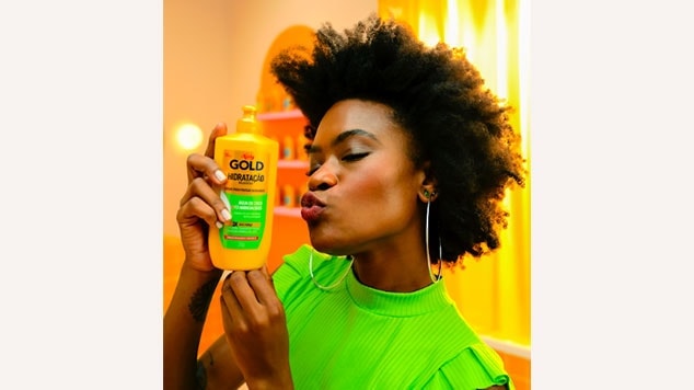 modelo negra segurando o shampoo de hidratação niely