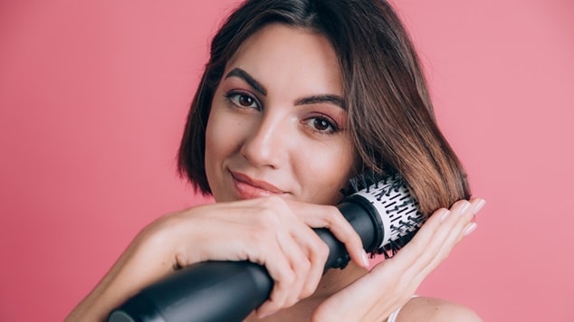 mulher branca utiliza escova secadora na potência e temperatura adequadas para seu cabelo curto
