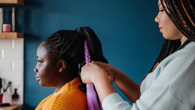 Profissional cabeleireira faz a manutenção e aplica um novo dread ou dreadlock em sua cliente