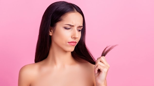 Pessoa com cabelo liso escuro segura uma mecha de cabelo, mostrando as pontas duplas.
