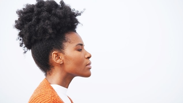 jovem com um elegante penteado crespo alto, preso em um coque, exibe a beleza e a força do cabelo natural.
