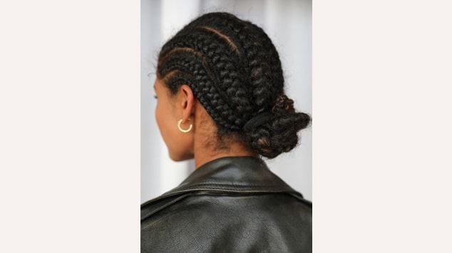 a versatilidade dos penteados para cabelo crespo, uma mulher exibe tranças laterais intrincadas que se juntam em um coque.