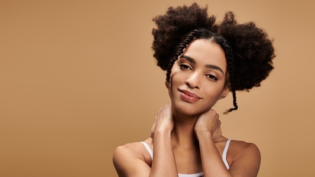 Penteado de formatura afro com dois coques e tranças laterais.