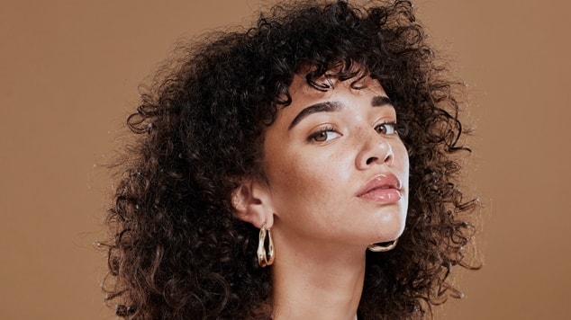 Penteado de formatura para cabelo cacheado natural com volume e franja.