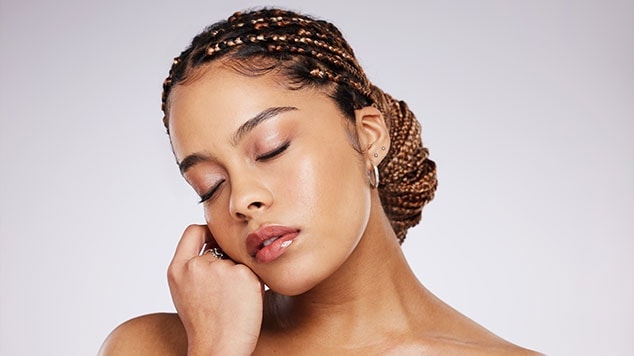 mulher com cabelos com tranças amarrado em coque baixo e com baby hair a mostra