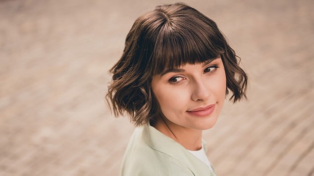 mulher com cabelo curto liso e franja olhando para o lado