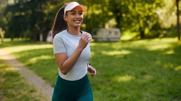 Mulher branca corre em um parque usando um penteado para corrida