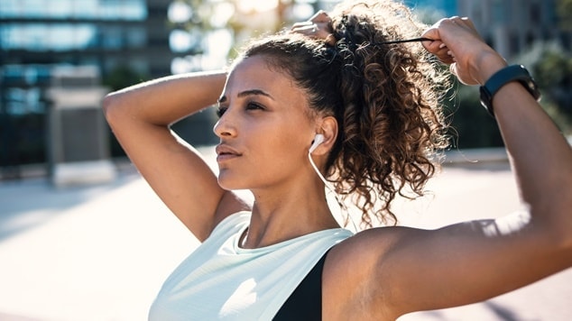 Mulher negra faz um rabo de cavalo alto em seu cabelo antes de começar a atividade física