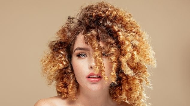 Menina com cabelo cacheado com luzes loiras.