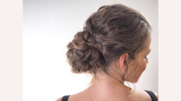 Mulher olhando para o lado direto com coque baixo no cabelo.