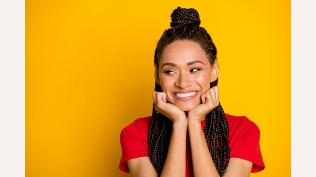 Mulher com as mãos apoiadas no rosto com coque e trança no cabelo.