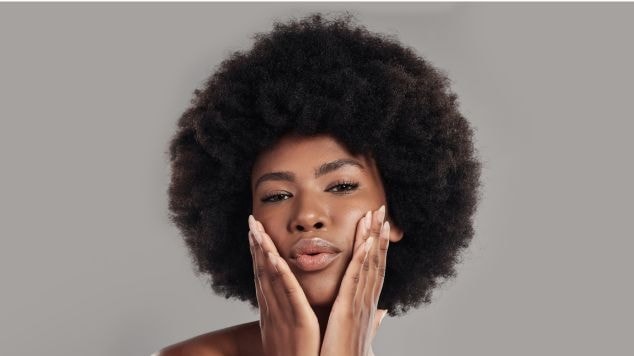 Mulher negra com cabelo crespo volumoso em estilo afro, exibindo pele radiante.