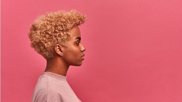 Perfil de mulher com cabelo crespo curto e loiro, demonstrando um estilo moderno e ousado.