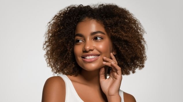 Mulher com cabelo crespo médio e sorriso radiante, mostrando a beleza e versatilidade dos cachos.