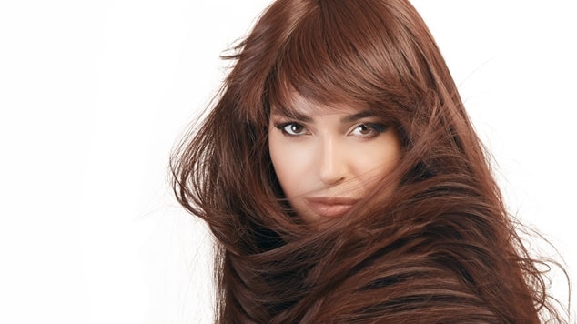 Mulher com cabelo castanho chocolate liso e brilhante cobrindo parte do rosto.