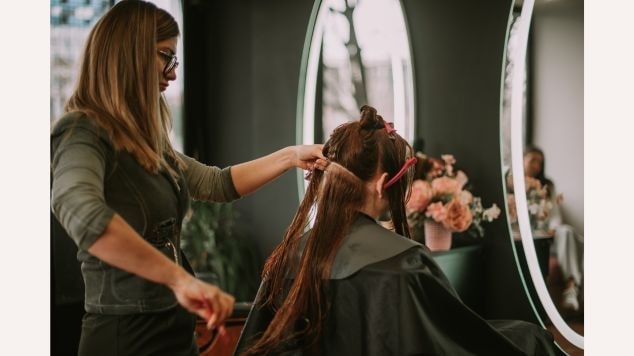 Profissional adicionando mechas castanho dourado no cabelo de sua cliente