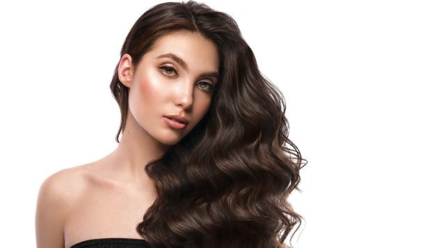 Mulher com cabelo castanho natural em fundo branco.