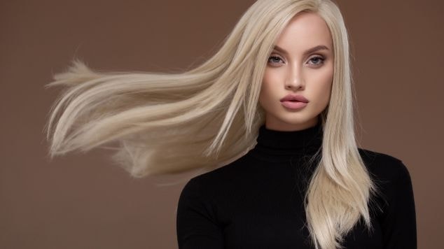 Mulher com cabelo loiro claro em fundo marrom.