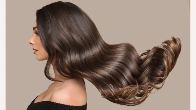 Mulher virada para o lado esquerdo com cabelo em tom loiro escuro acinzentado aos ventos.