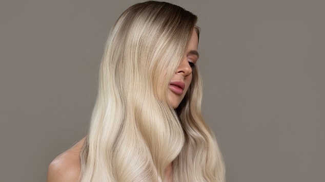 Mulher loira platinada com seu cabelo cobrindo grande parte de seu rosto.