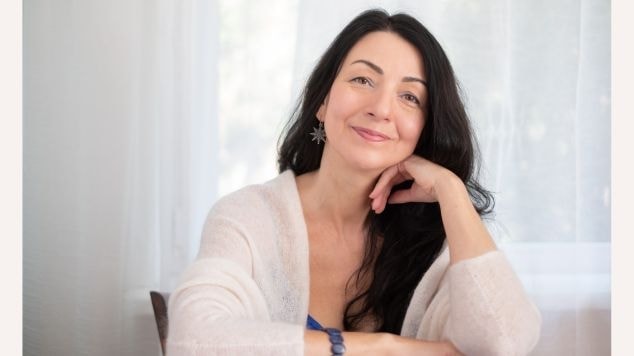 Mulher sorrindo com a mão no rosto e cabelo pintado com tinta de cabelo preto.
