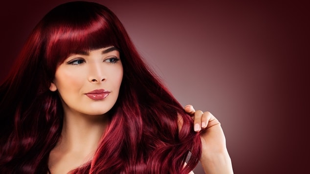 Mulher com cabelo vinho em fundo marrom.