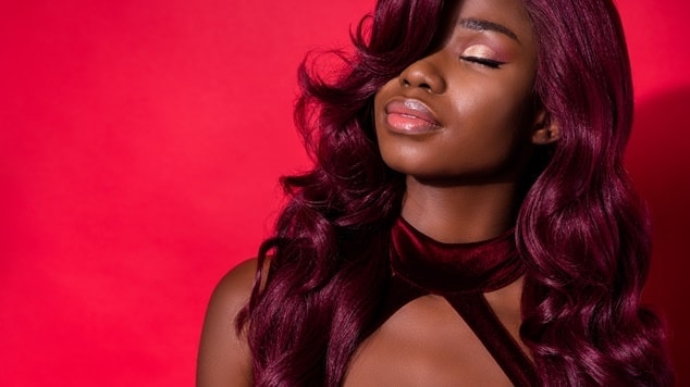 Mulher com tom de cabelo violine em fundo vermelho.