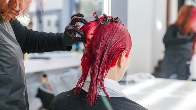 Mulher pintando o cabelo de vermelho cereja escuro