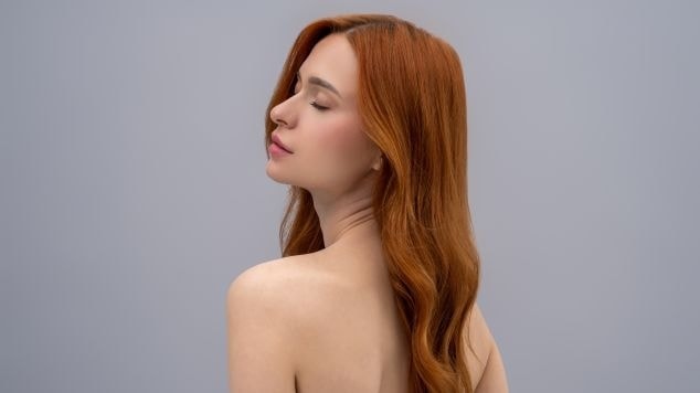 Mulher de cabelos longos ruivo doce de leite, de perfil, com pele clara e expressão serena, destacando a luminosidade e brilho da coloração.