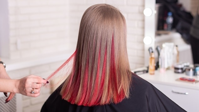 Mechas em tom vermelho em cabelo loiro médio.