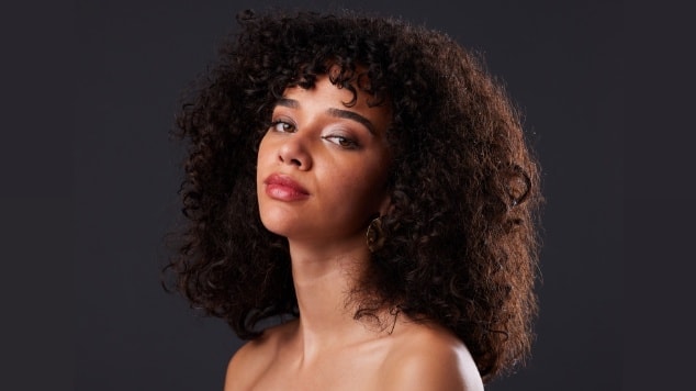 Mulher com cabelo castanho escuro olhando para a câmera.