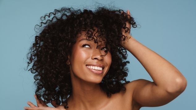 Mulher sorridente mostrando seu cabelo castanho escuro.