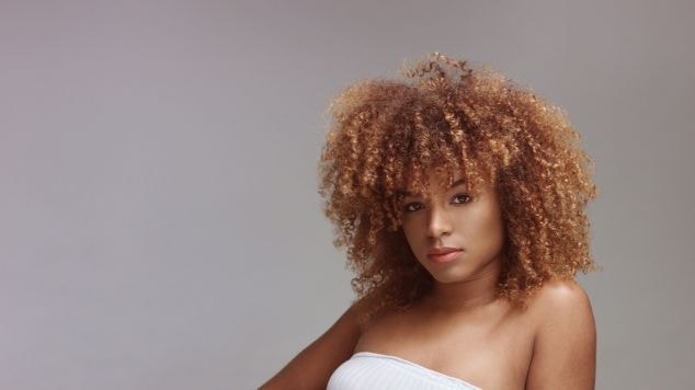 Mulher negra com cabelo loiro acobreado.
