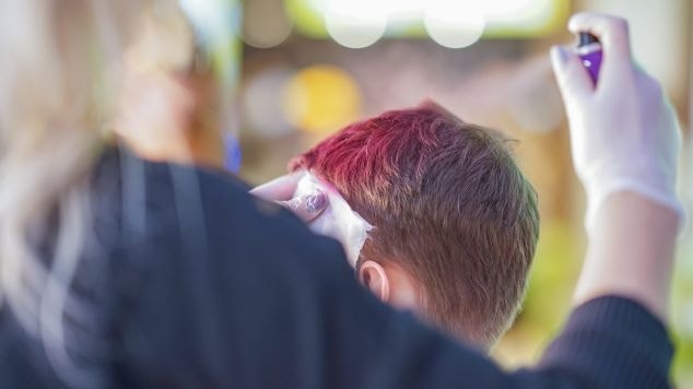 Mulher pinta os fios com um spray para pintar cabelos coloridos