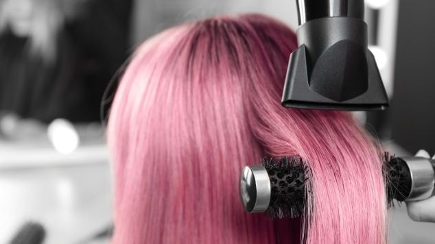 Profissional secando o cabelo colorido após pintar