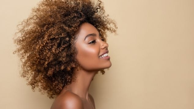 Mulher olhando para o lado direito sorrindo.