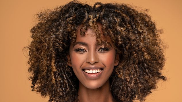 Mulher sorridente com cabelo cacheado.