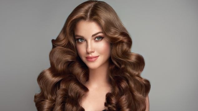 Mulher com cabelo marrom chocolate em fundo cinza.