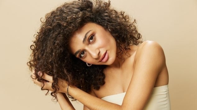 Mulher com cabelo marrom em fundo bege.