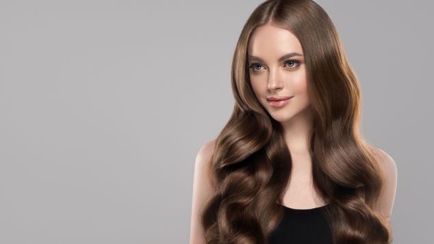 Mulher com cabelo marrom em fundo cinza.