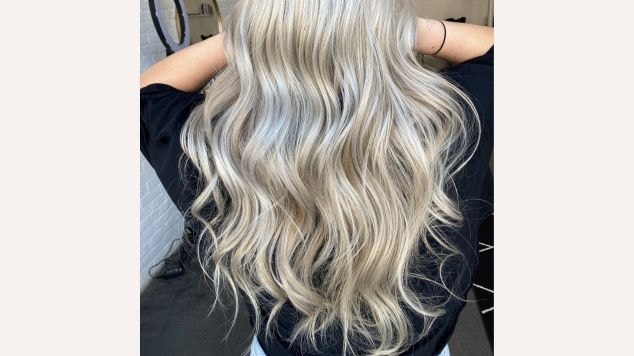 Cabelo platinado longo com ondas suaves e reflexos prateados, ideal para um visual moderno e elegante.
