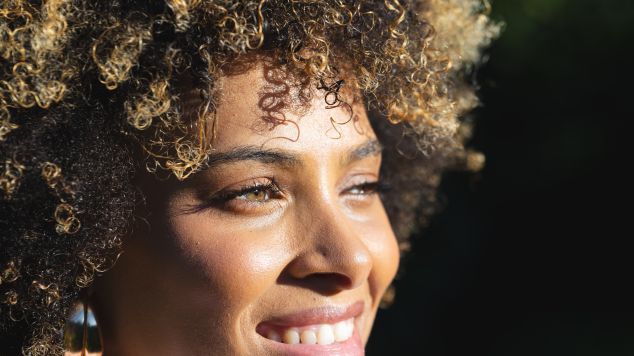 Mulher negra com o cabelo crespo opta por disfarçar o cabelo branco ao fazer luzes no cabelo