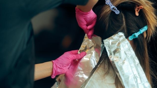 Profissional aplica luzes no cabelo de sua cliente no salão de beleza