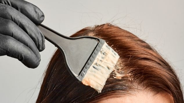 Mulher pintando o cabelo sozinha de ruivo.